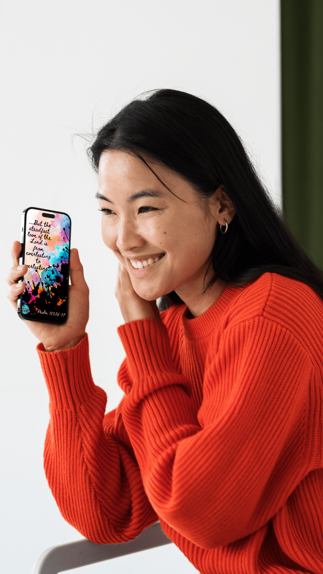 Woman in a red sweater holding a smartphone with the floral design inspired by Psalm 103: "Everlasting to Everlasting" 