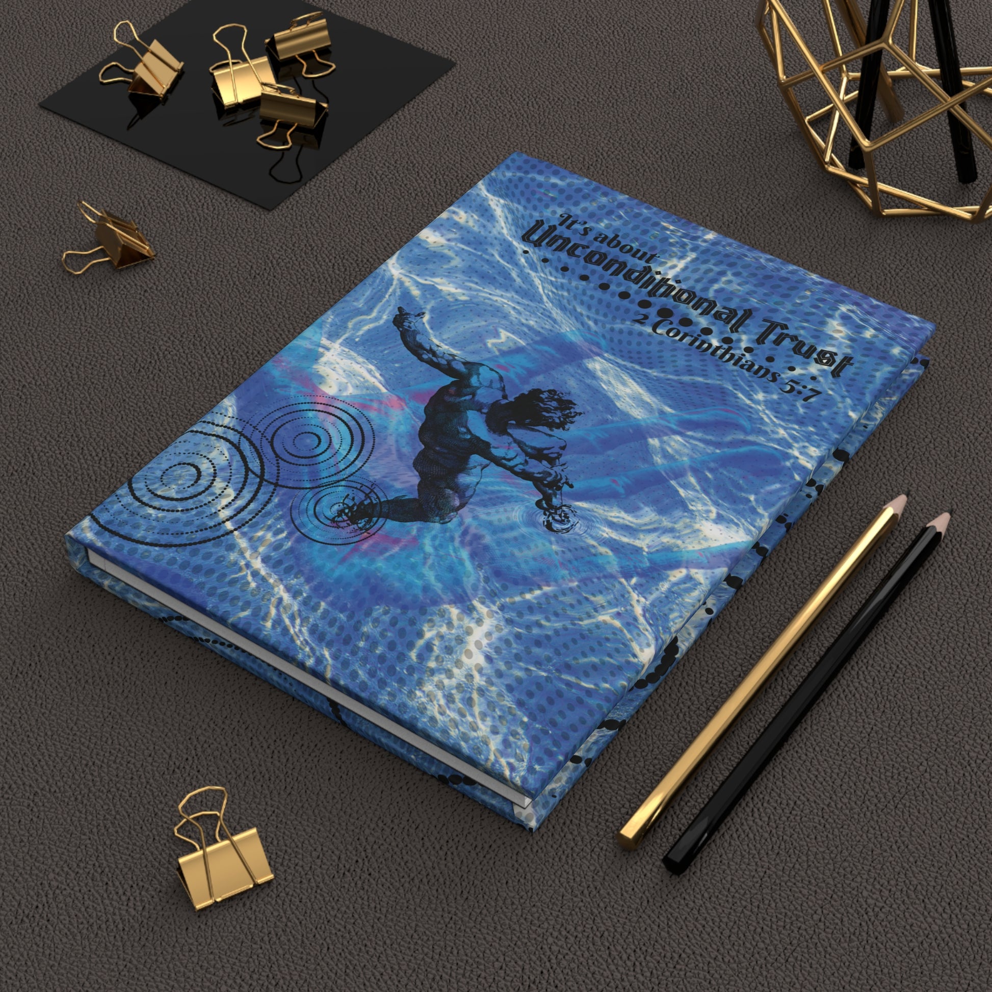 The Unconditional Trust Hardcover Christian Journal displayed on a leather desk mat beside several pencils and clips—perfect for Bible study, journaling, or devotional time.