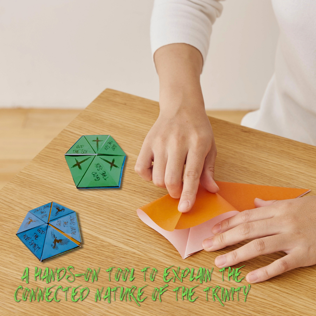 Someone folding orange paper on a wood table surface, with two completed Unfolding the Trinity flexagons sitting next to them. Text over lay says: A hands on tool to explain the connected nature of the Trinity. 